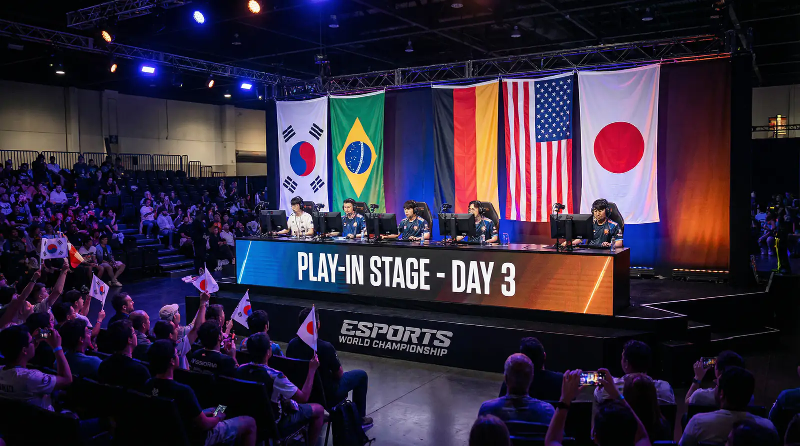 Equipos de eSports compitiendo en escenario de Play-In con banderas internacionales